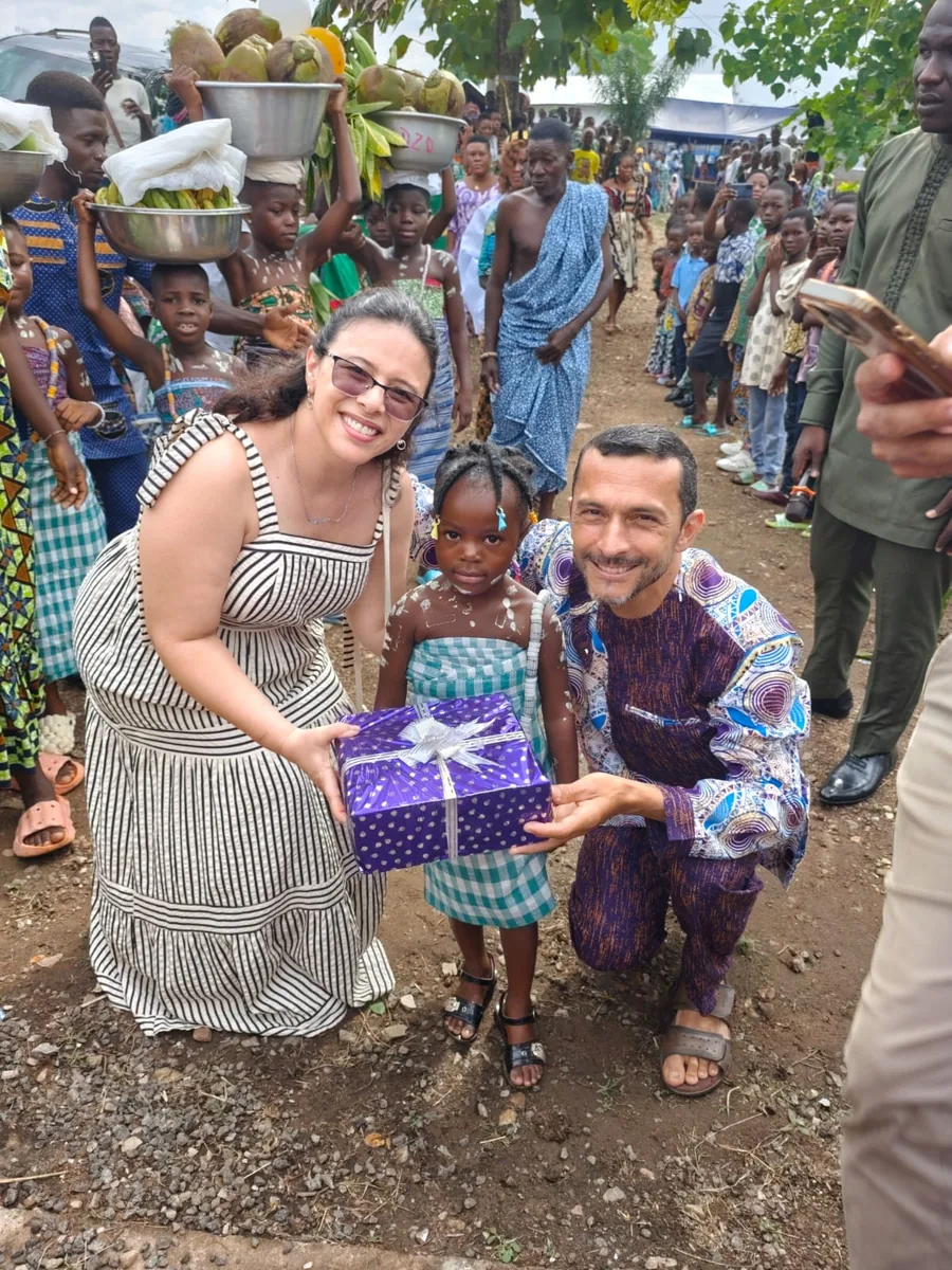 O missionário Josinaldo e sua esposa entregam um presente embrulhado a uma menina, cercados por crianças do vilarejo