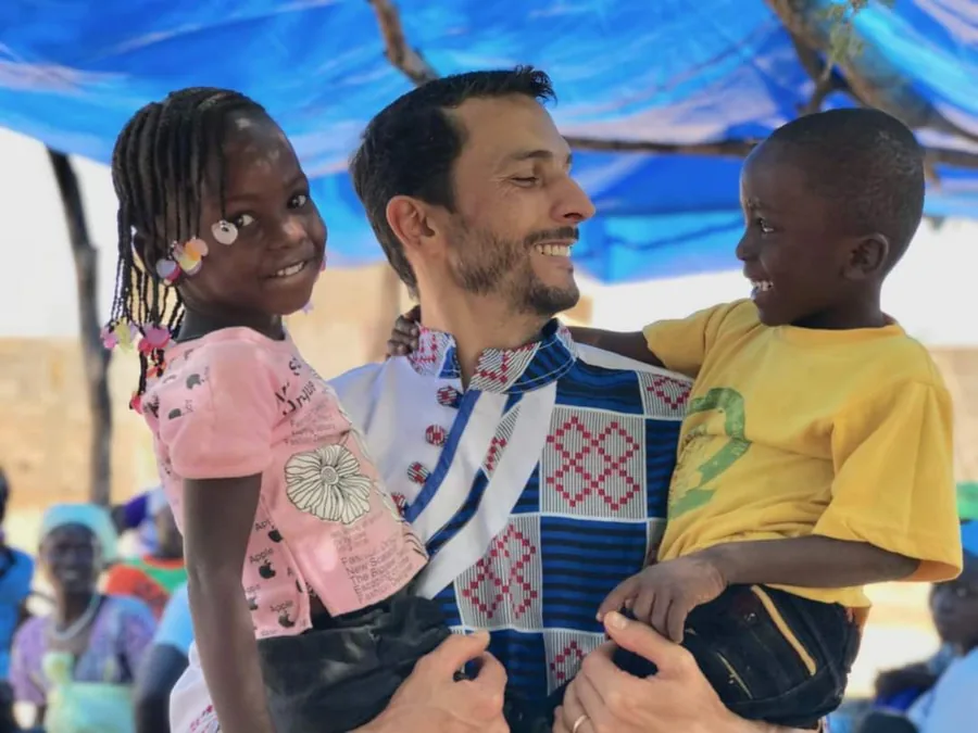 O missionário Josinaldo com duas crianças no colo, sorrindo
